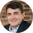 portrait of a smiling white man against a brick wall